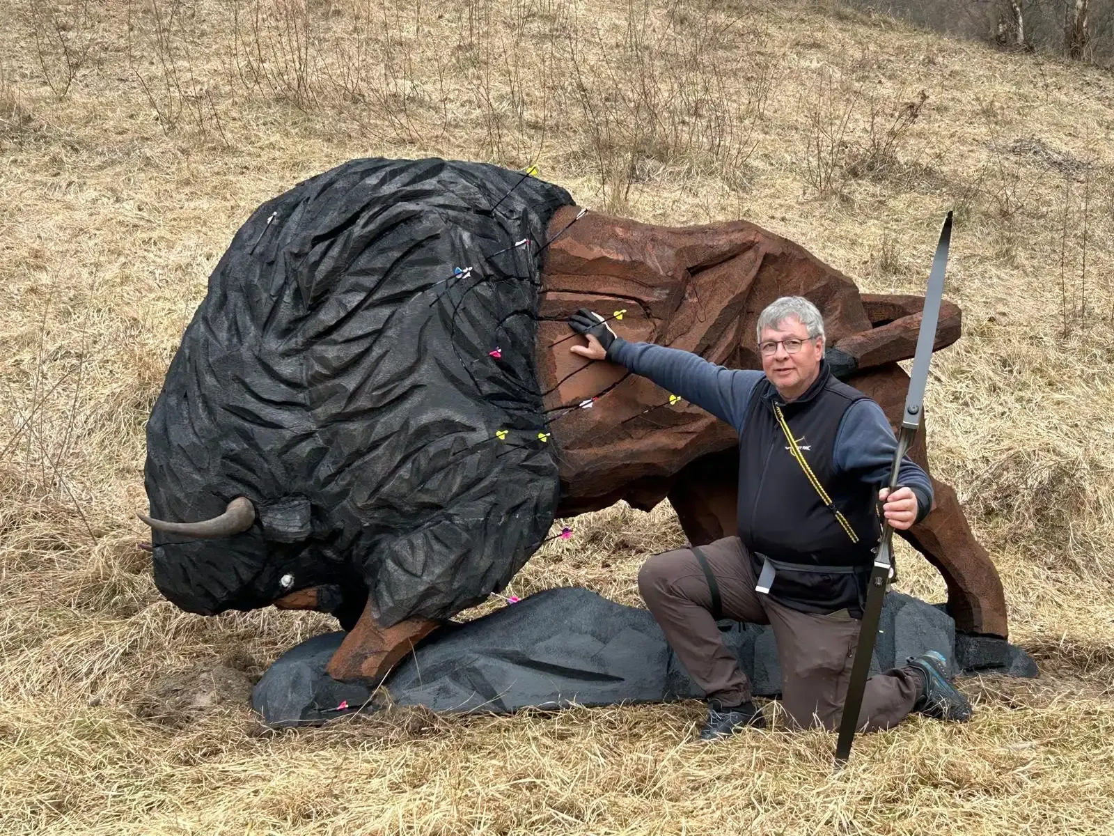 Siegfried Pritzi kniet mit Bogen neben einem 3D-Bisonziel voller Pfeile